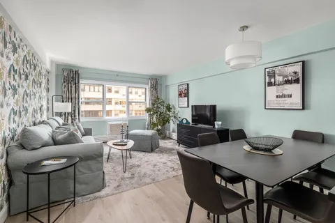 a living room with furniture a flat screen tv and a large window