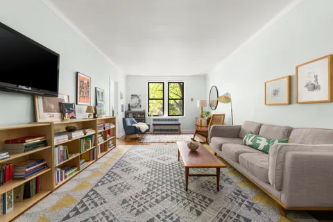 a living room with furniture a flat screen tv and a window