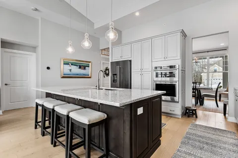 a kitchen with stainless steel appliances granite countertop a table chairs refrigerator and sink