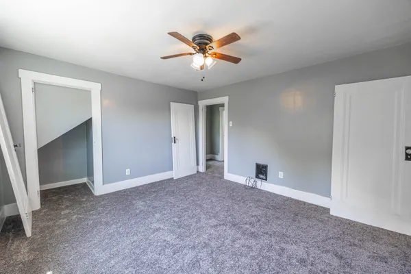 an empty room with windows and fan