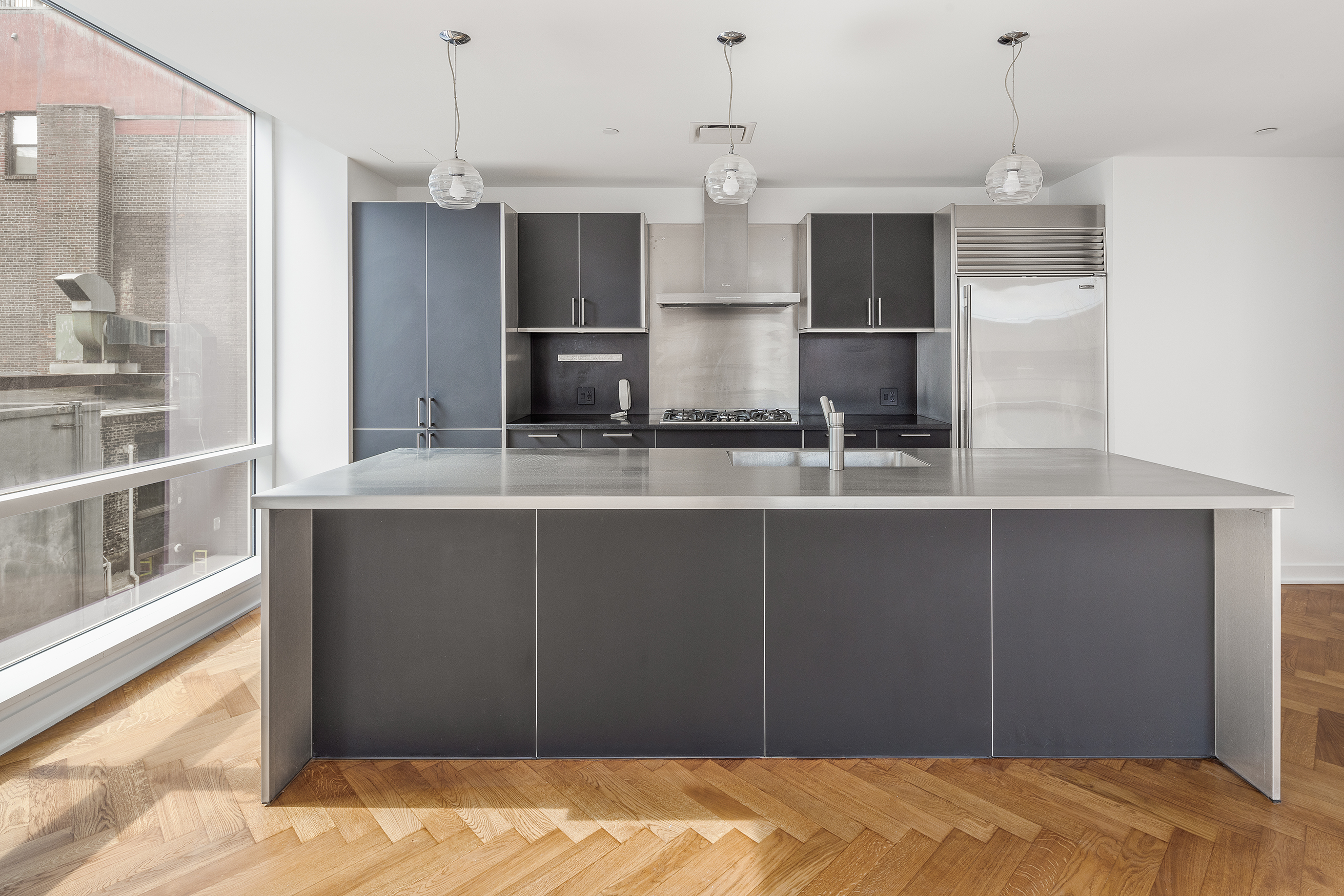 330 Spring Street, Unit 5A Manhattan, NY 10013 - Photo 6 of 13 a kitchen with kitchen island a counter top space stainless steel appliances and cabinets