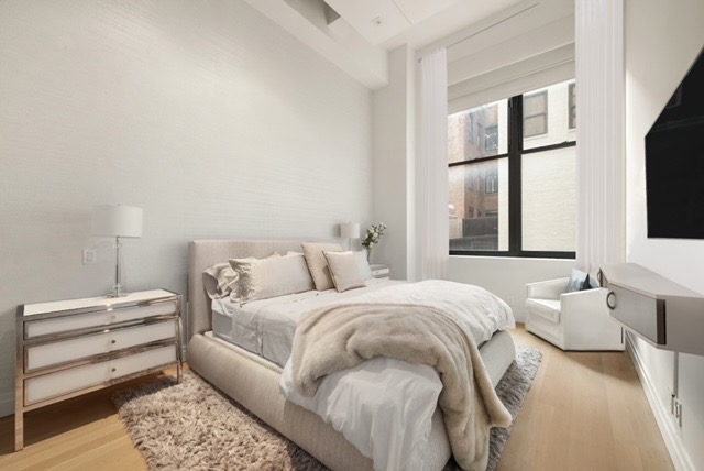 421 Hudson Street, Unit 320 Manhattan, NY 10014 - Photo 6 of 13 a bedroom with a bed and a flat tv screen on a dresser