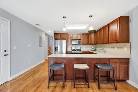 a kitchen with stainless steel appliances granite countertop a table chairs refrigerator and wooden cabinets