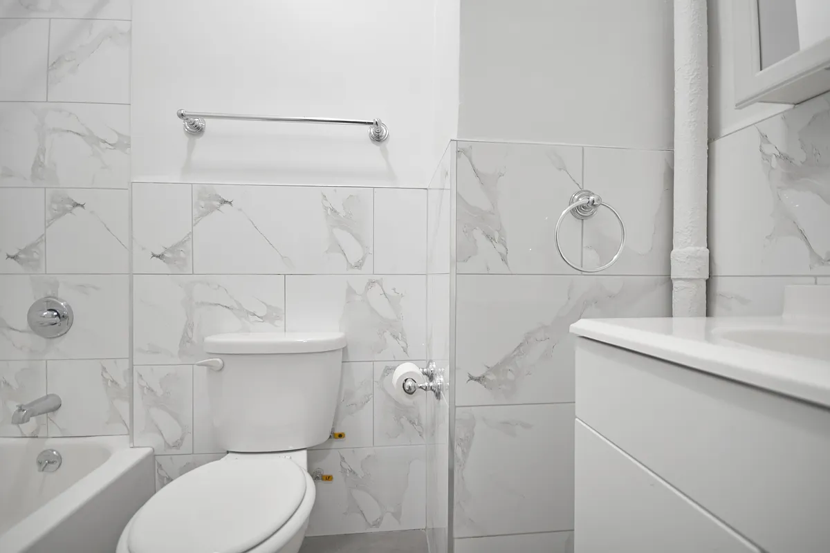 209 East 88th Street, Unit 4B Manhattan, NY 10128 - Photo 5 of 5 a bathroom with a granite countertop sink toilet and shower