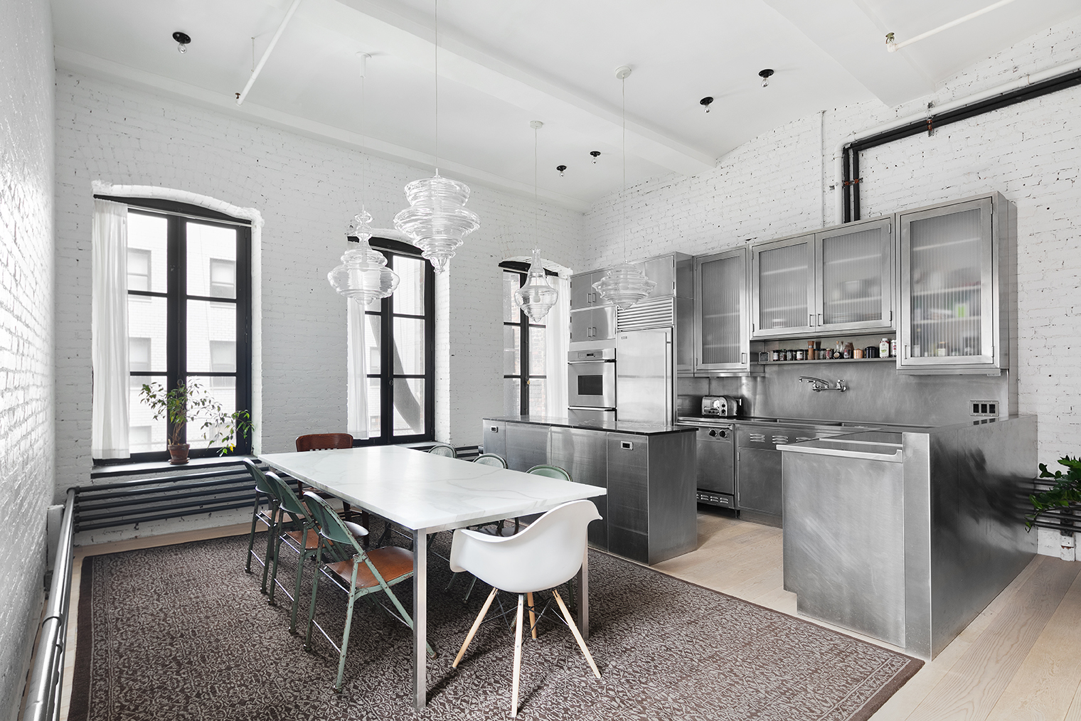 59 4th Avenue, Unit 2B Manhattan, NY 10003 - Photo 3 of 14 a dining room with stainless steel appliances kitchen island granite countertop a table chairs and a refrigerator