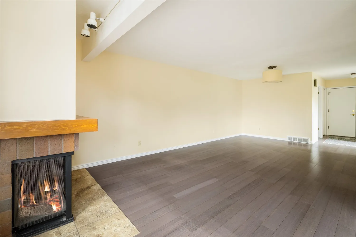 a view of an empty room with wooden floor and a fireplace