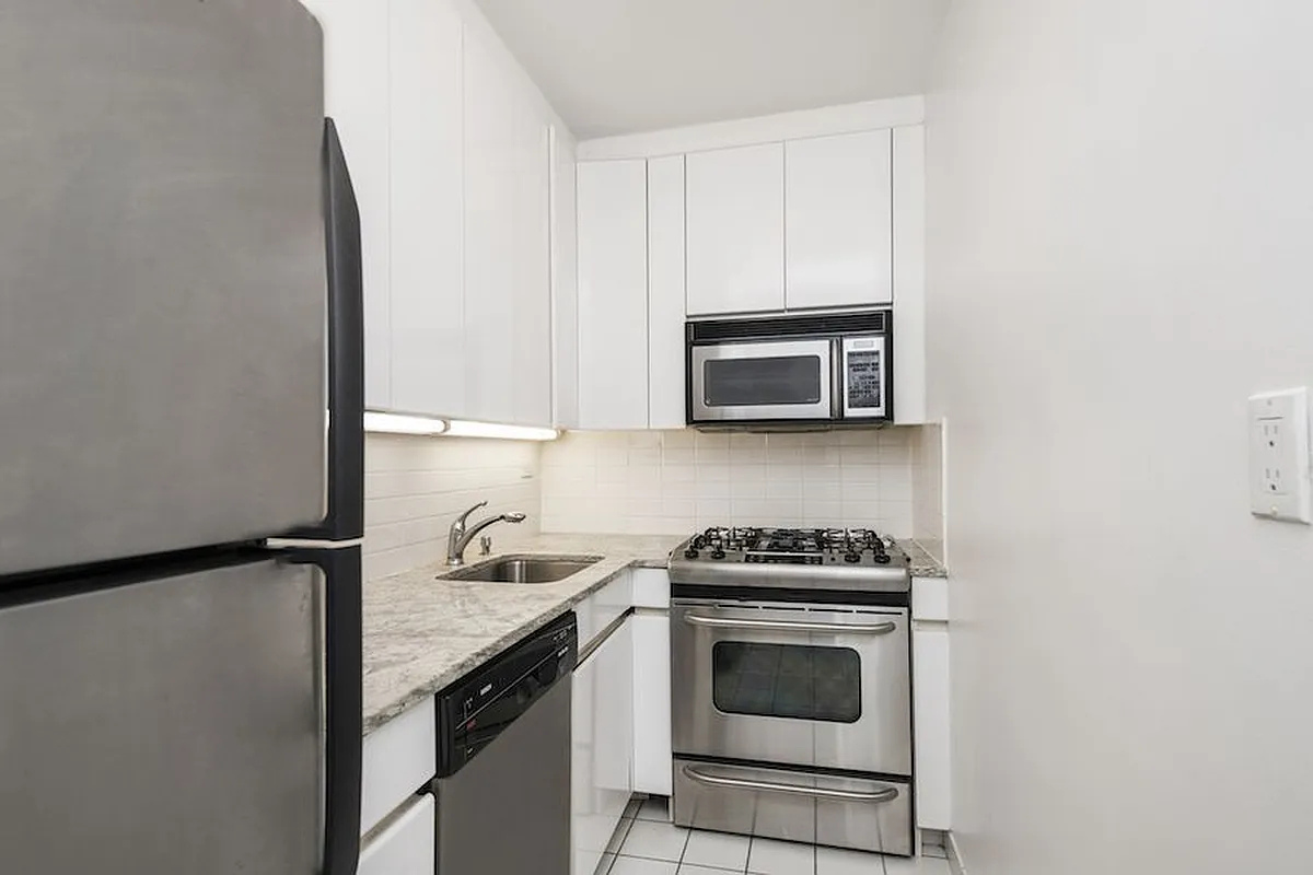 211 East 53rd Street, Unit 14B Manhattan, NY 10022 - Photo 3 of 8 a kitchen with granite countertop a stove and a microwave