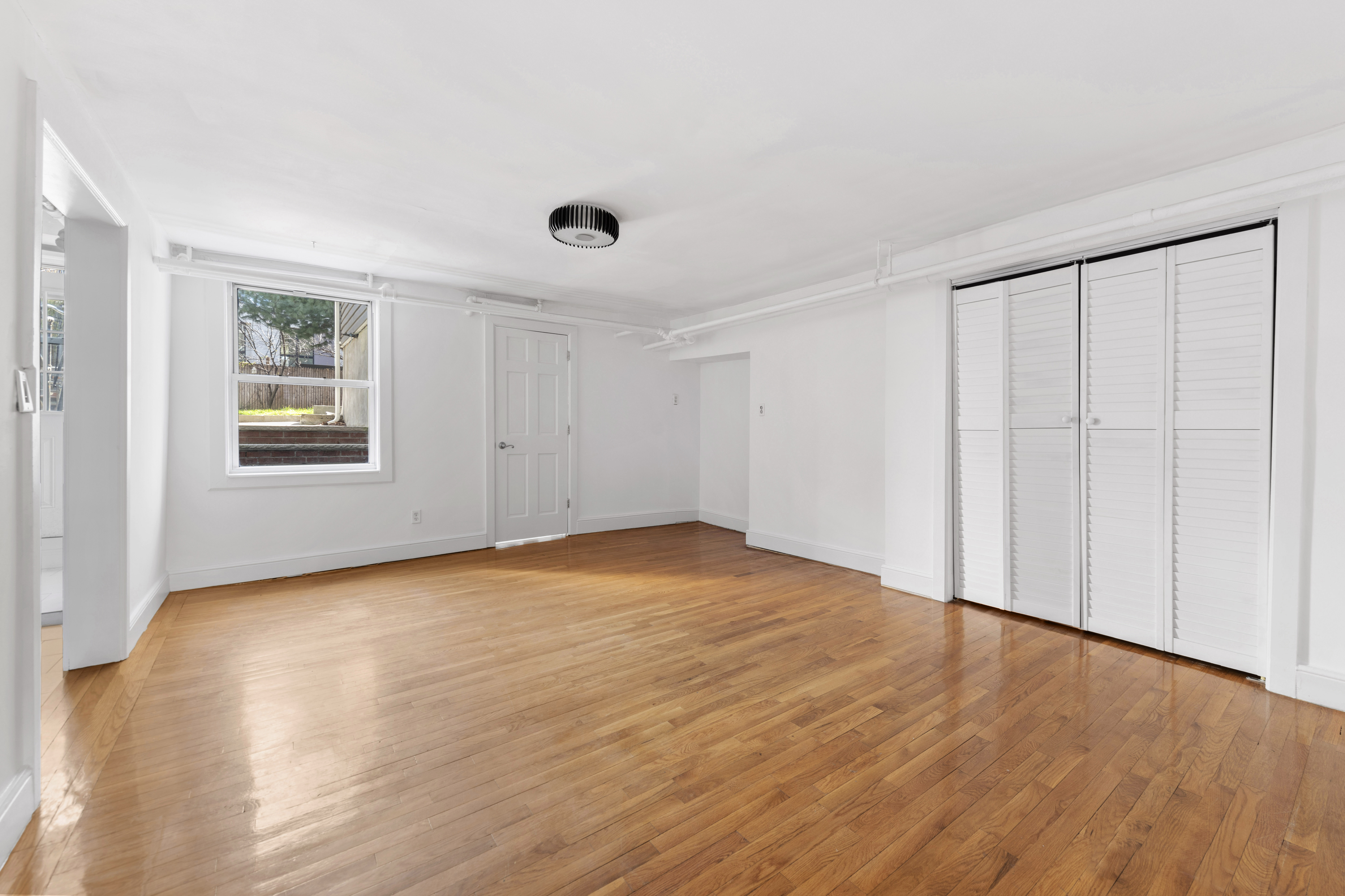 20 Devoe Street, Unit GF Brooklyn, NY 11211 - Photo 3 of 6 a view of an empty room with wooden floor and a window