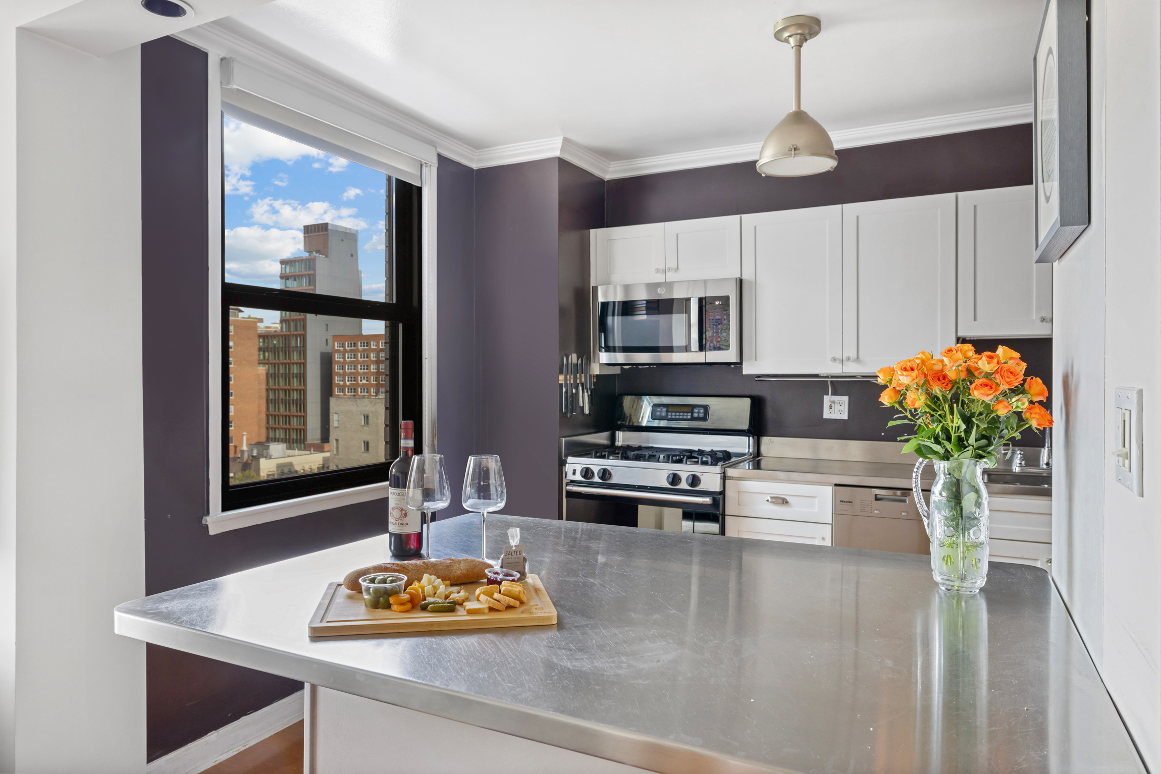 130 East 18th Street, Unit 14B Manhattan, NY 10003 - Photo 3 of 8 a kitchen with stainless steel appliances kitchen island granite countertop a stove and white cabinets