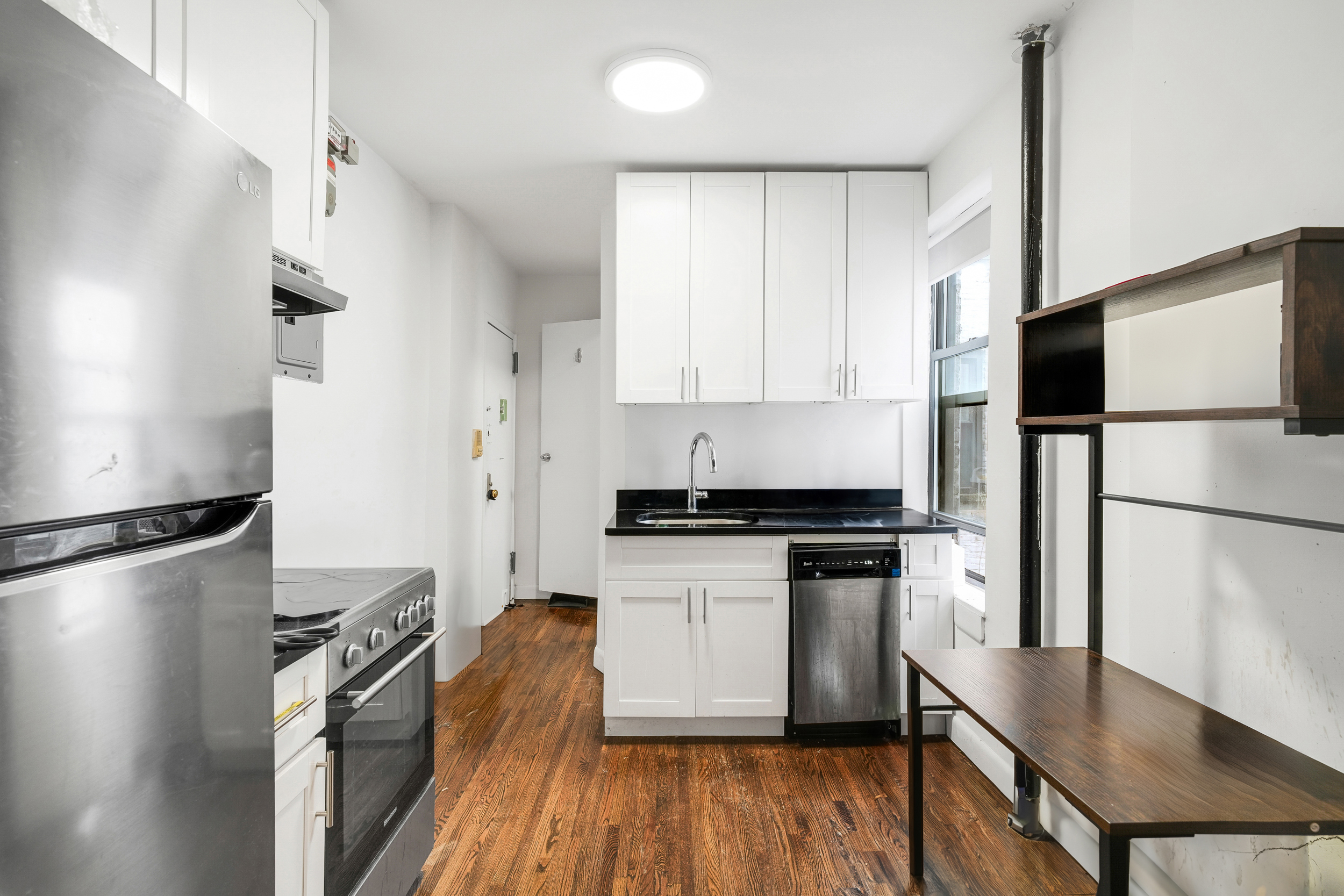 214 East 82nd Street, Unit 27 Manhattan, NY 10028 - Photo 1 of 6 a kitchen with stainless steel appliances granite countertop a refrigerator a stove a sink and a microwave