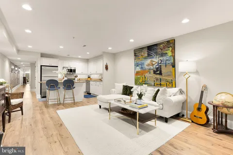 a living room with furniture and kitchen view with wooden floor