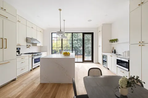 a living room with kitchen island granite countertop furniture a kitchen island a stove a sink dishwasher and white cabinets with wooden floor