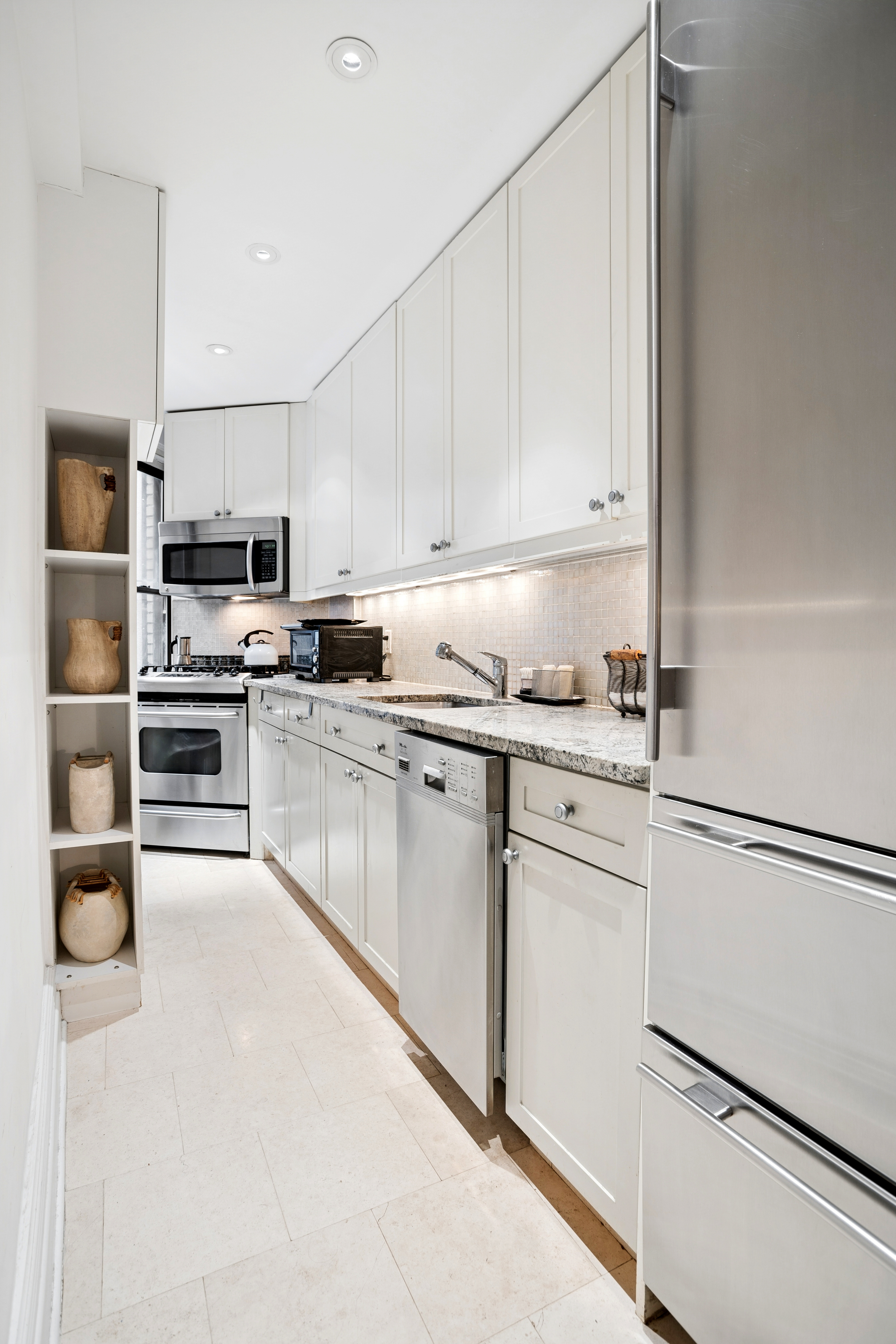 865 1st Avenue, Unit 9C Manhattan, NY 10017 - Photo 3 of 13 a kitchen with granite countertop white cabinets and stainless steel appliances
