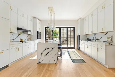 a large white kitchen with white cabinets and wooden floor