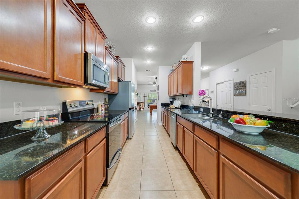 352 Giovani Boulevard Clermont, FL 34715 - Photo 10 of 46 a large kitchen with stainless steel appliances granite countertop a sink a stove and a wooden cabinets
