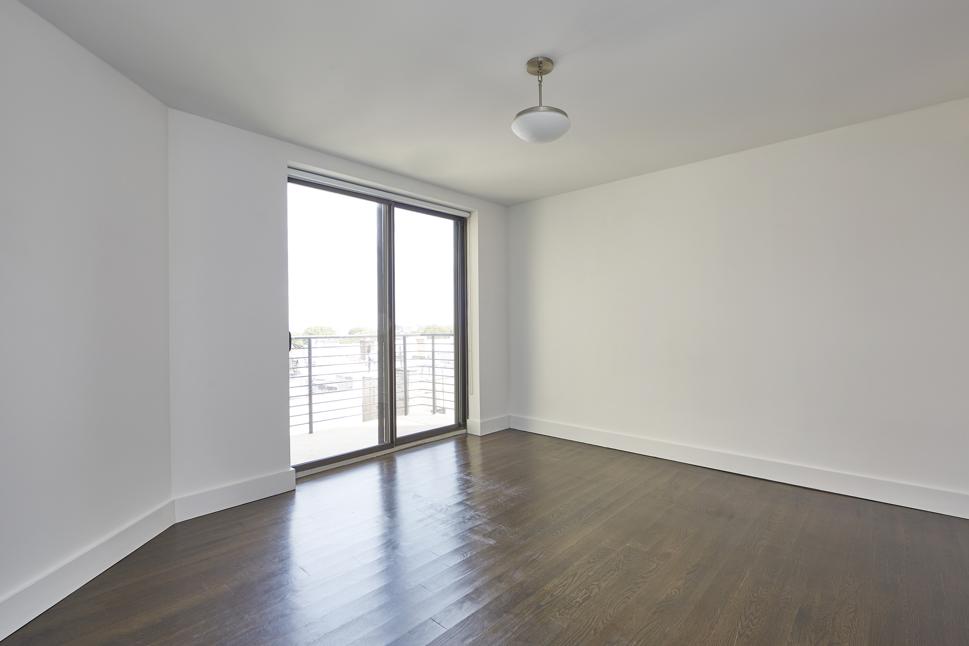 341 Eastern Parkway, Unit 8D Brooklyn, NY 11216 - Photo 7 of 7 an empty room with wooden floor and windows with curtains view