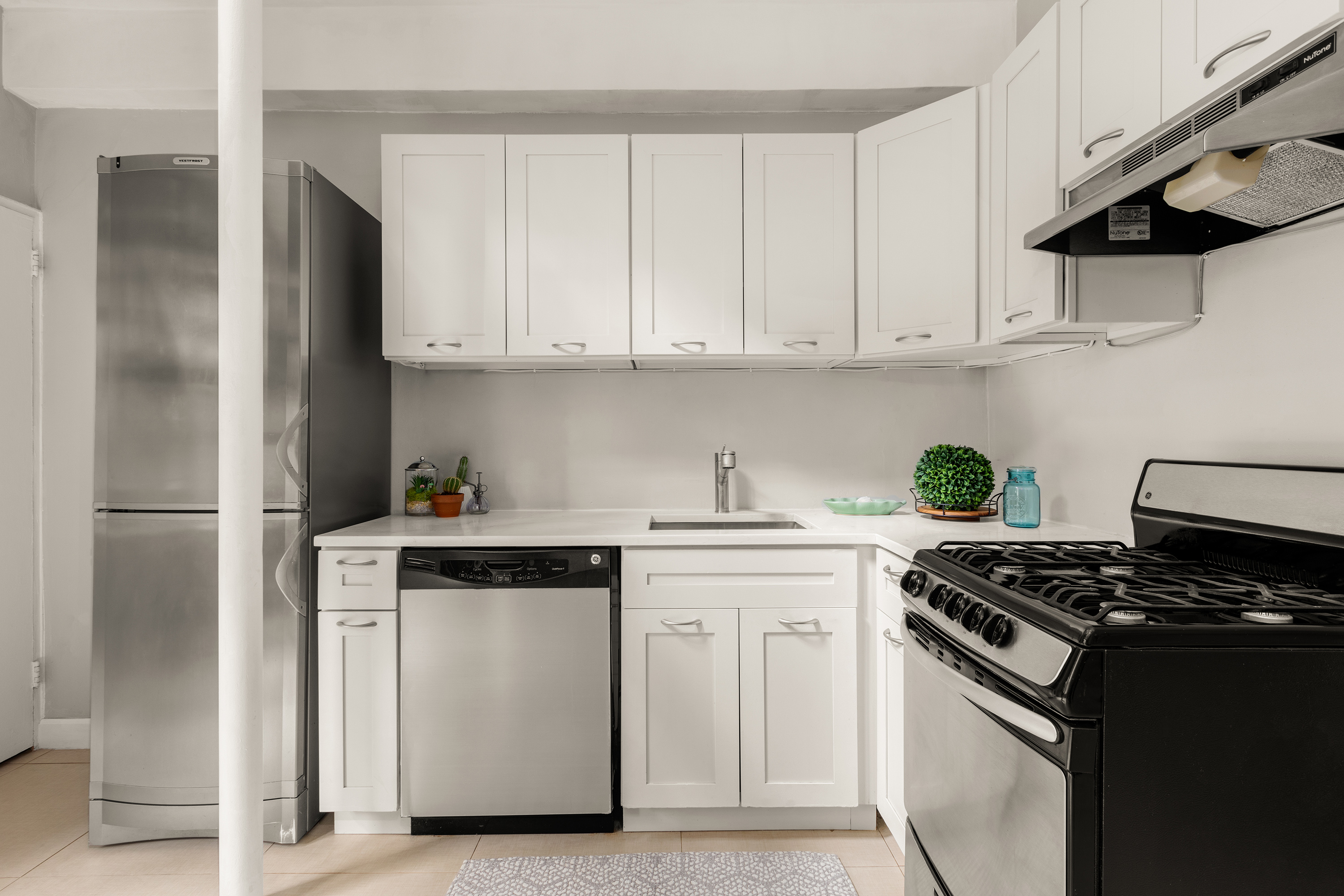 342 East 53rd Street, Unit 1G Manhattan, NY 10022 - Photo 3 of 9 a kitchen with stainless steel appliances granite countertop white cabinets and a stove top oven