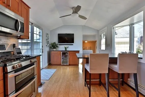 a kitchen with stainless steel appliances granite countertop a stove top oven a sink dishwasher a dining table and chairs with wooden floor
