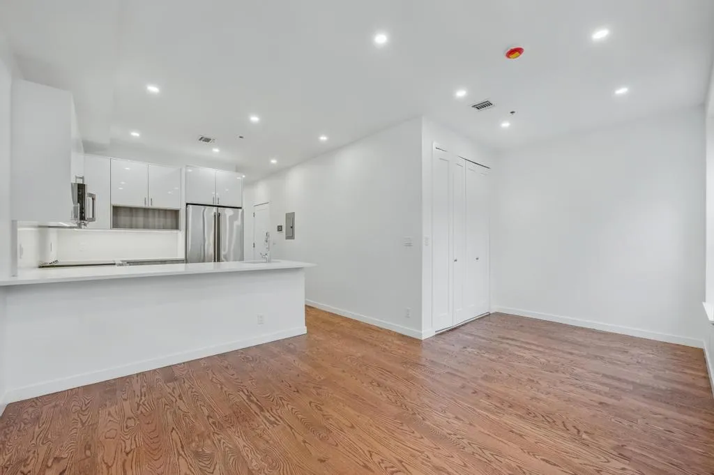 a view of kitchen with kitchen island wooden floor center island and stainless steel appliances