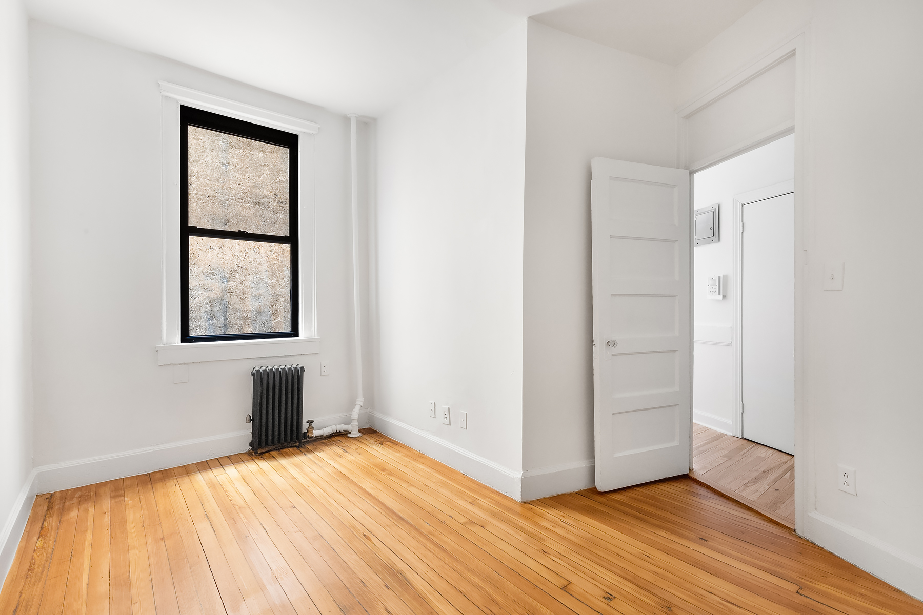 149 Sullivan Street, Unit 3D Manhattan, NY 10012 - Photo 5 of 8 a view of an empty room with wooden floor and a window