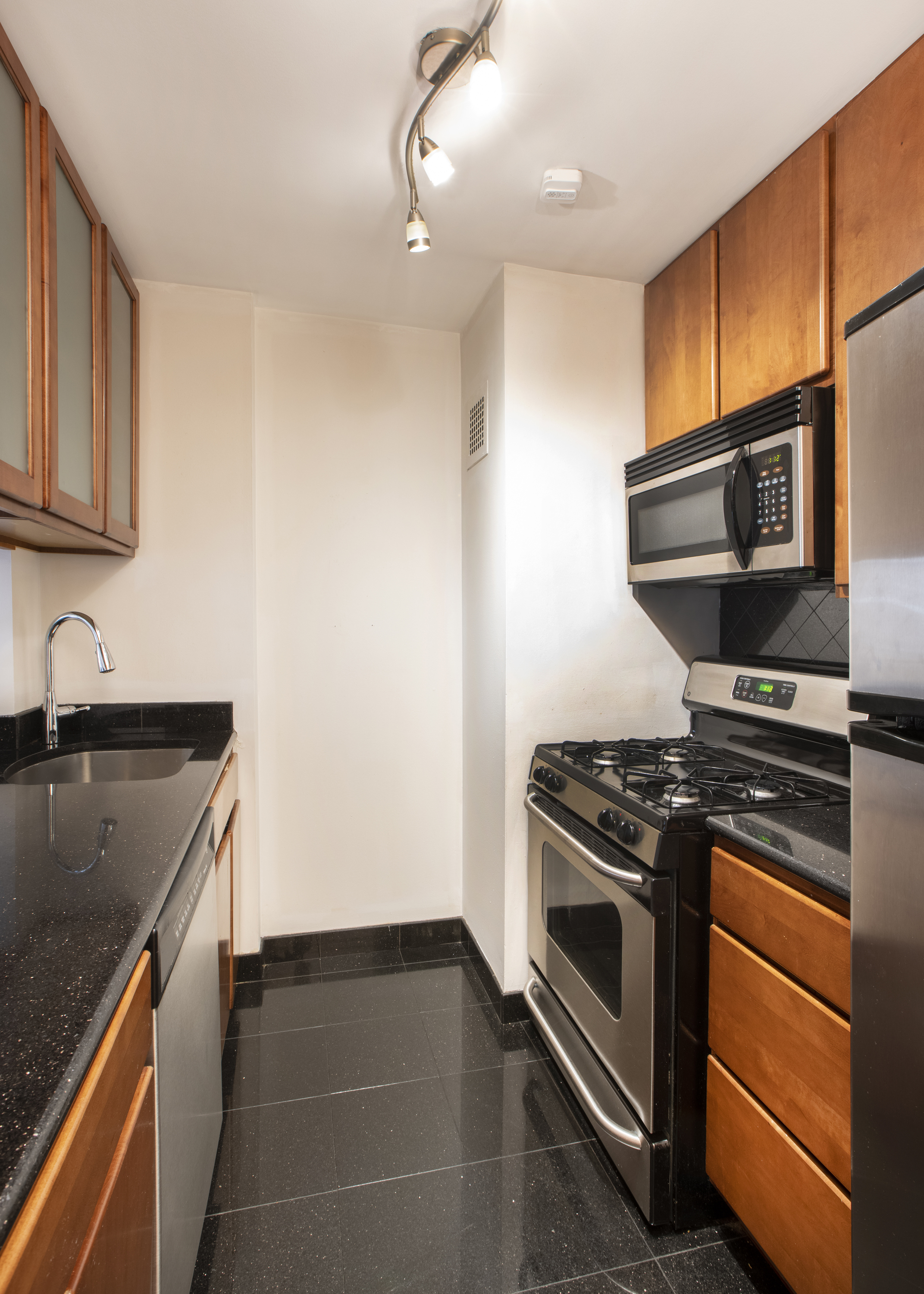 300 East 59th Street, Unit 803 Manhattan, NY 10022 - Photo 4 of 14 a kitchen with granite countertop a stove sink and microwave