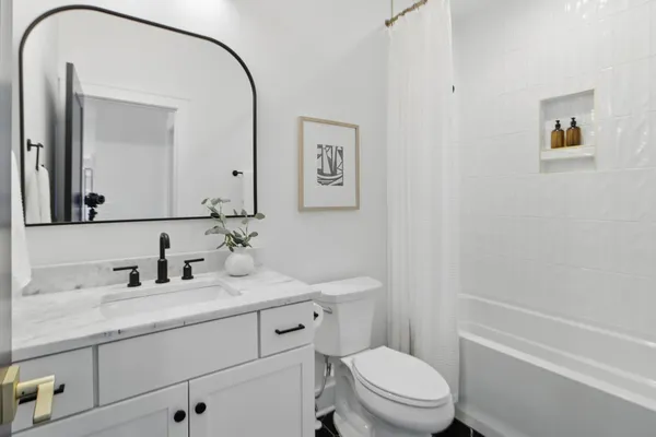 a bathroom with a toilet a sink a mirror and a shower