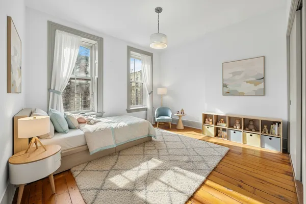 a spacious bedroom with a bed a couch and large window