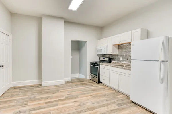 a kitchen with granite countertop a refrigerator sink stove and cabinets