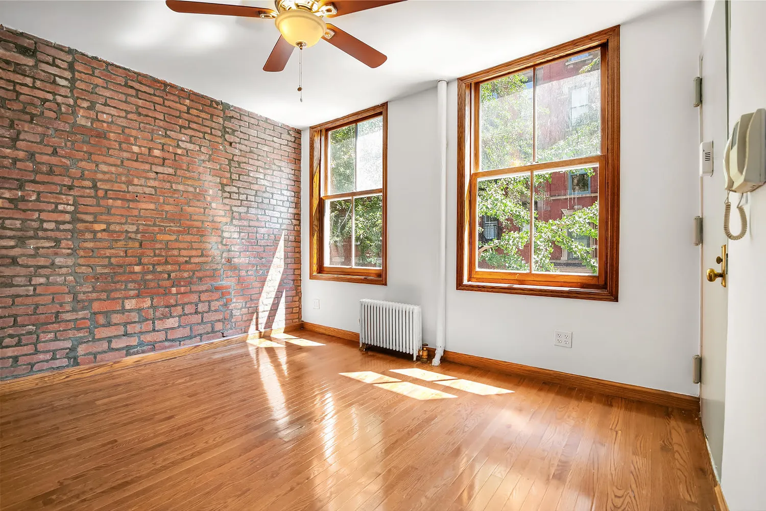 a view of an empty room with a window and wooden floor