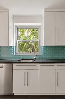 a sink with white cabinets and a window