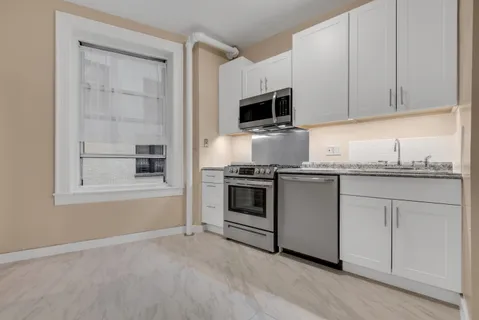 a kitchen with granite countertop white cabinets and stainless steel appliances