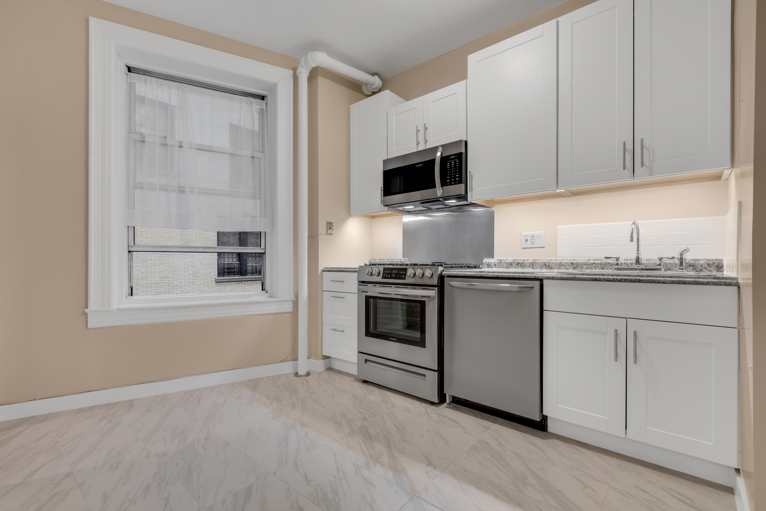 251 West 98th Street, Unit 1B Manhattan, NY 10025 - Photo 7 of 9 a kitchen with granite countertop white cabinets and stainless steel appliances