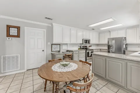 a kitchen with stainless steel appliances granite countertop a sink a stove a kitchen island with chairs and white cabinets