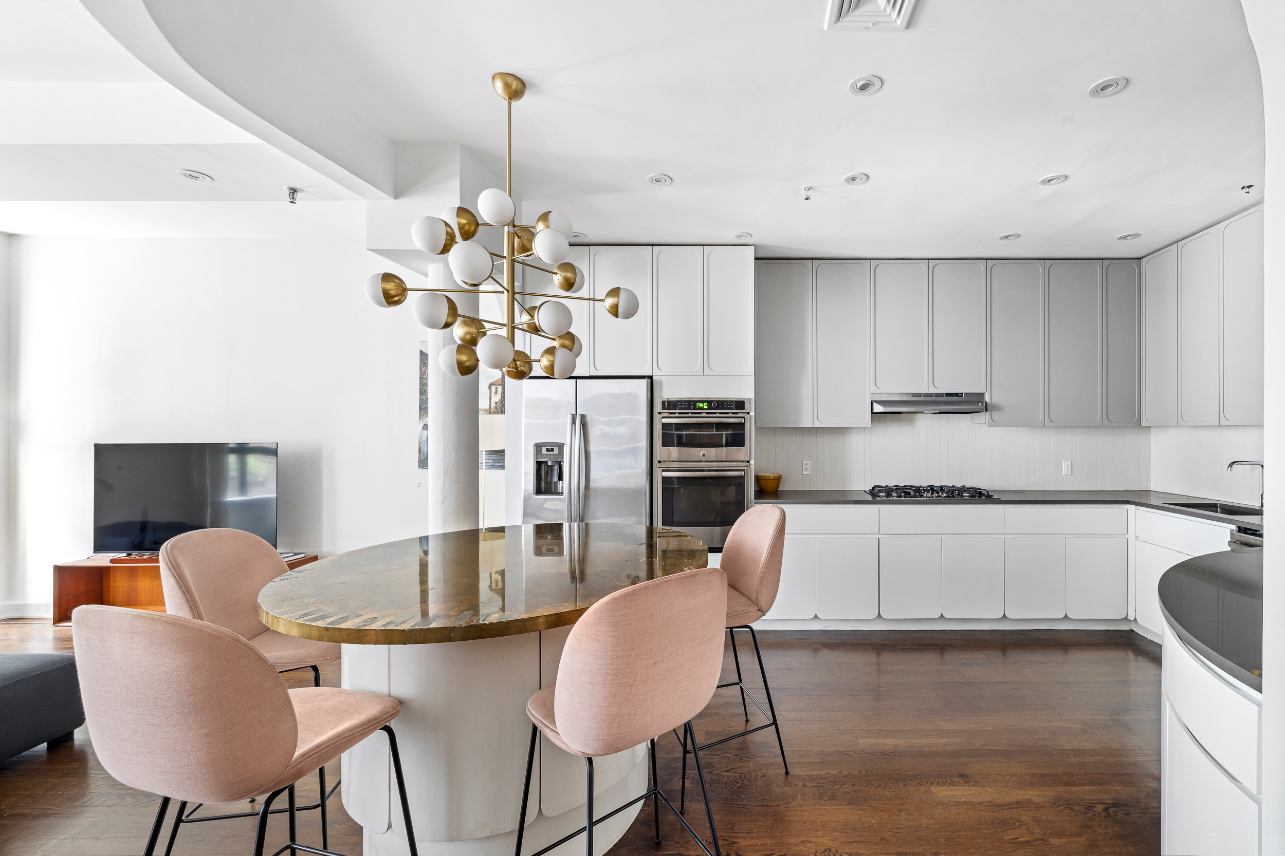 240 West 23rd Street, Unit 3/4C Manhattan, NY 10011 - Photo 4 of 13 a kitchen with stainless steel appliances granite countertop a table chairs stove and refrigerator