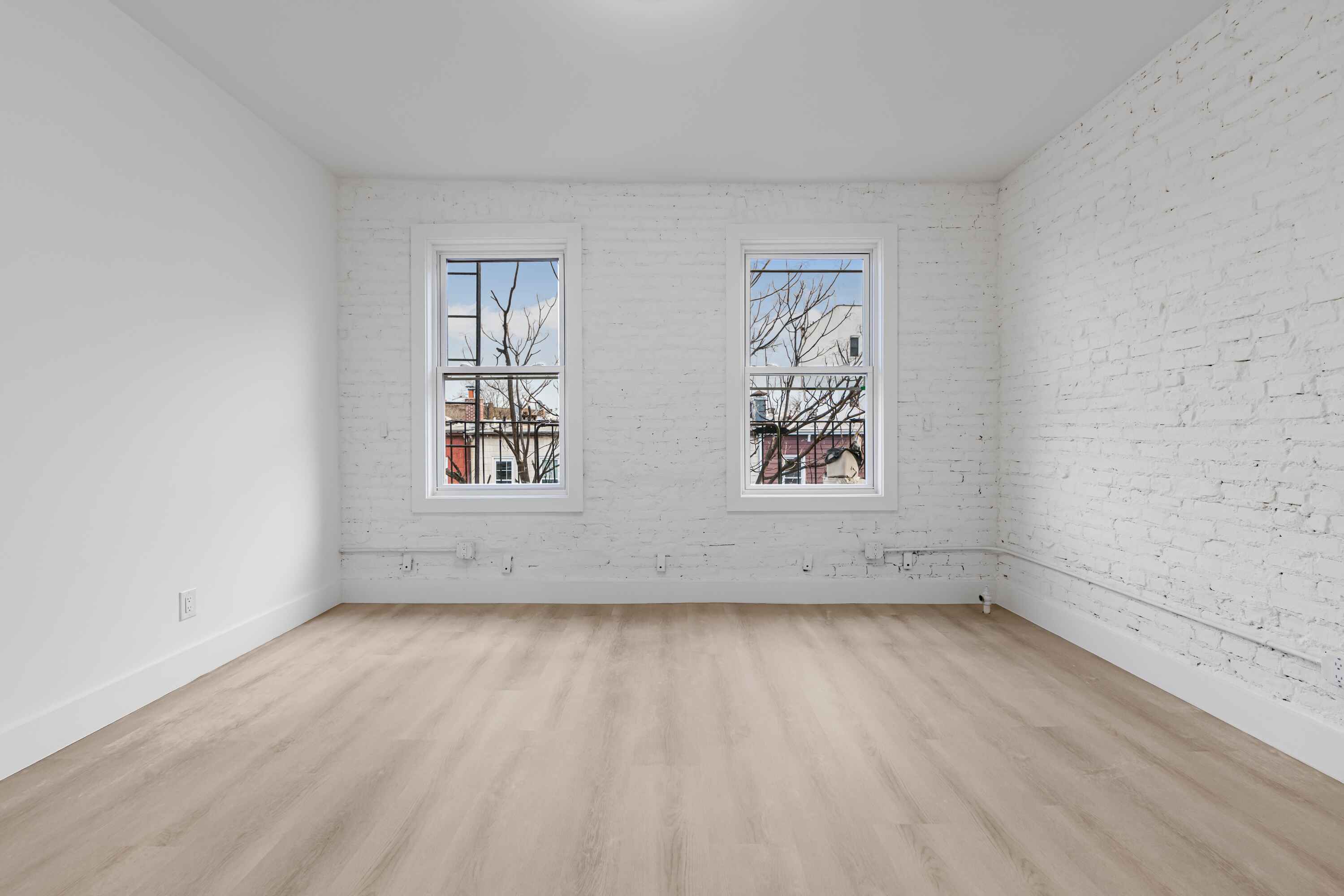 23-13 Steinway Street, Unit 2F Queens, NY 11105 - Photo 2 of 10 an empty room with wooden floor and windows