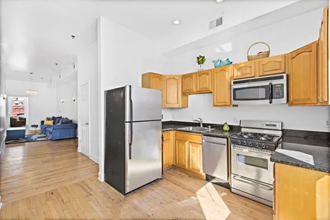 a kitchen with stainless steel appliances granite countertop a refrigerator a stove and a sink