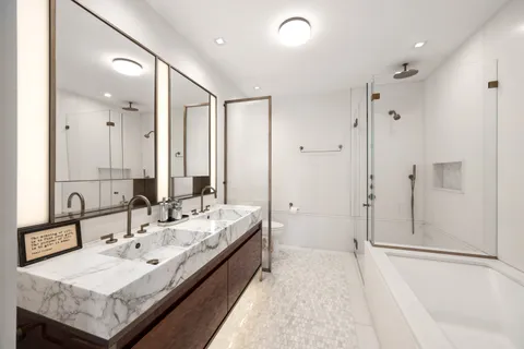 a spacious bathroom with a tub sink and mirror