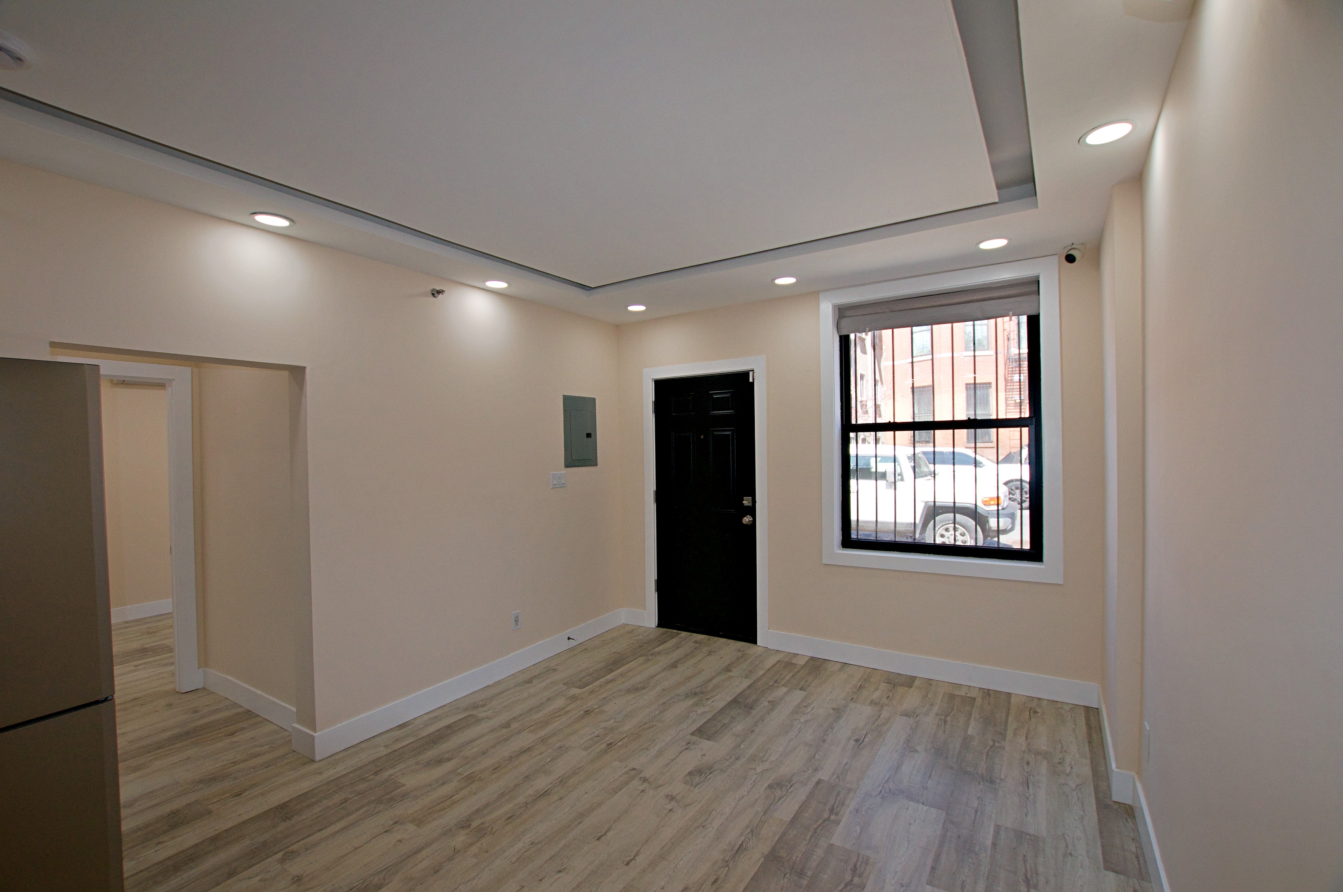 220 Madison Street, Unit 1A Brooklyn, NY 11216 - Photo 5 of 9 a view of an empty room with wooden floor and a window