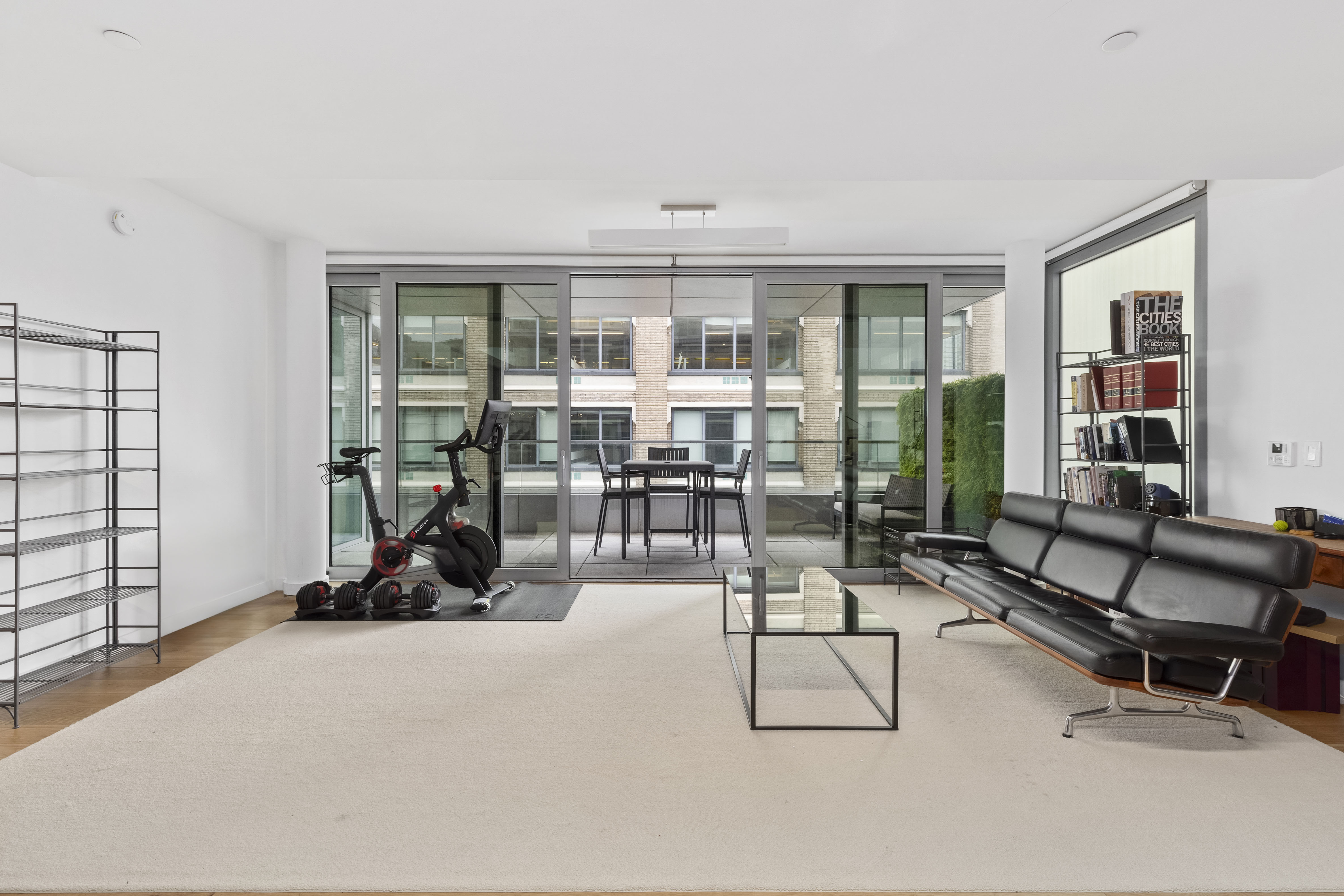 a living room with furniture gym equipment and floor to ceiling window