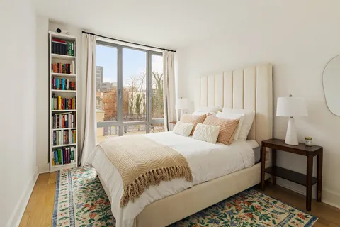 a bedroom with a bed a table and a large window