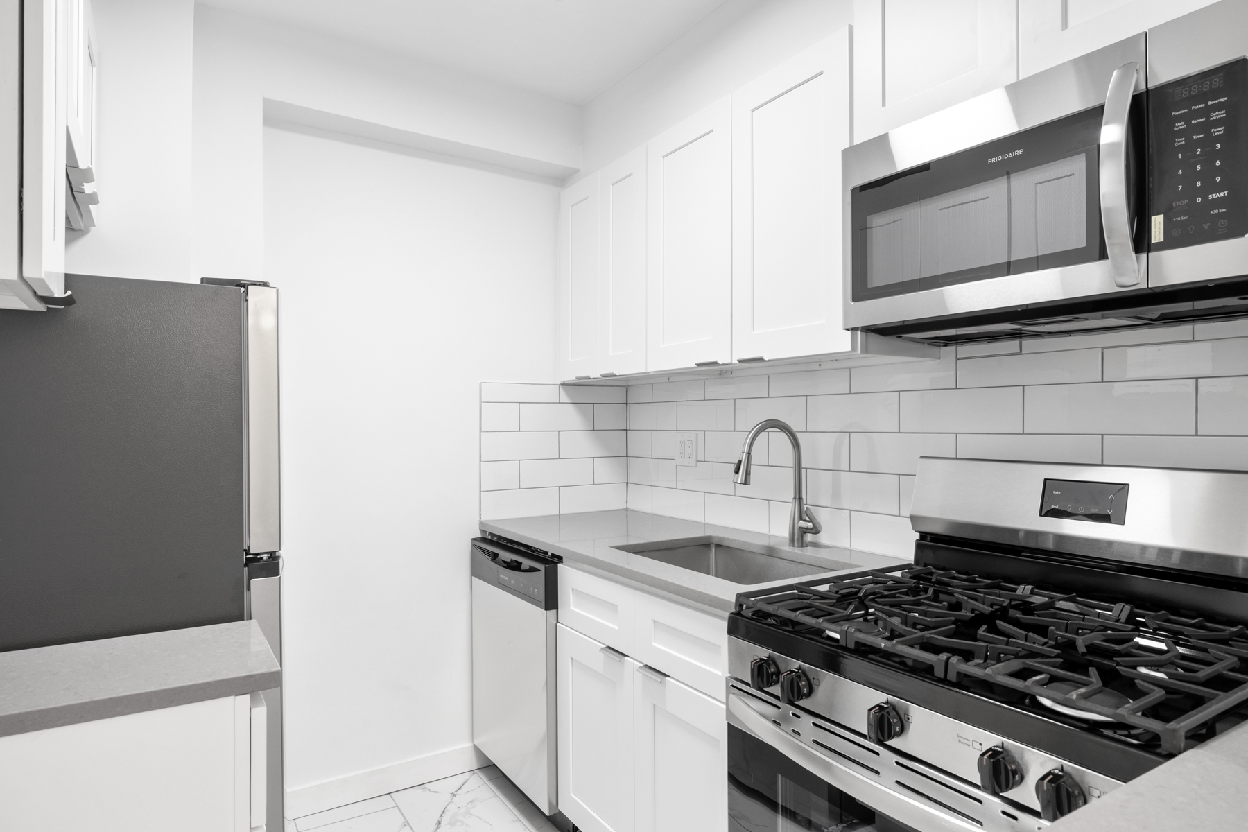 35-20 Leverich Street, Unit B226 Queens, NY 11372 - Photo 6 of 15 a kitchen with stainless steel appliances granite countertop white cabinets and black stove top oven