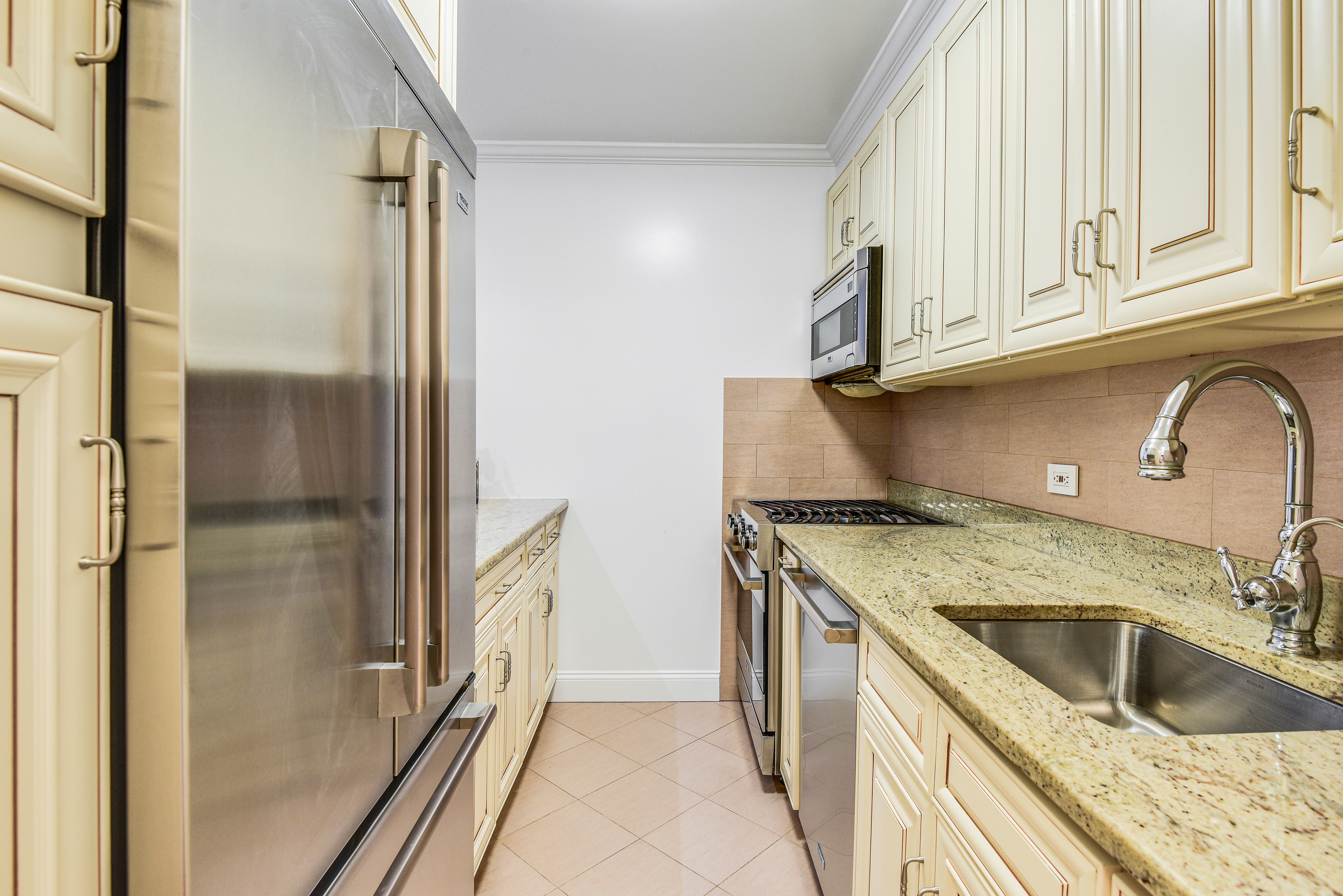 200 Central Park South, Unit 5M Manhattan, NY 10019 - Photo 10 of 15 a kitchen with granite countertop a sink stove and refrigerator