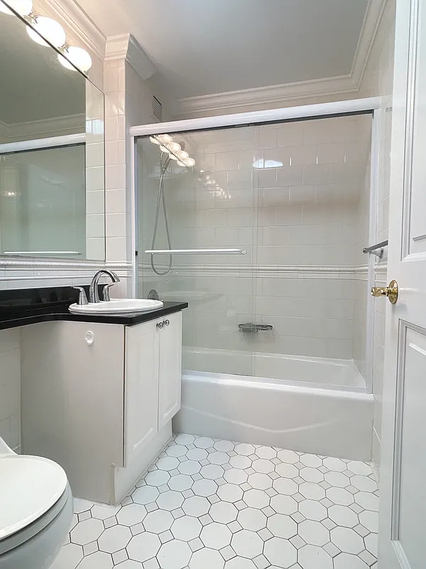 400 East 90th Street, Unit 15B Manhattan, NY 10128 - Photo 9 of 15 a bathroom with a granite countertop sink a toilet a mirror and shower