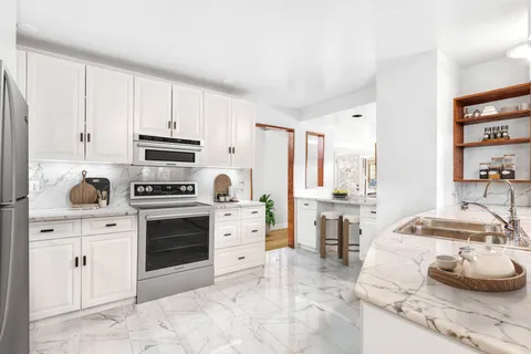 a kitchen with stainless steel appliances a stove a sink and white cabinets