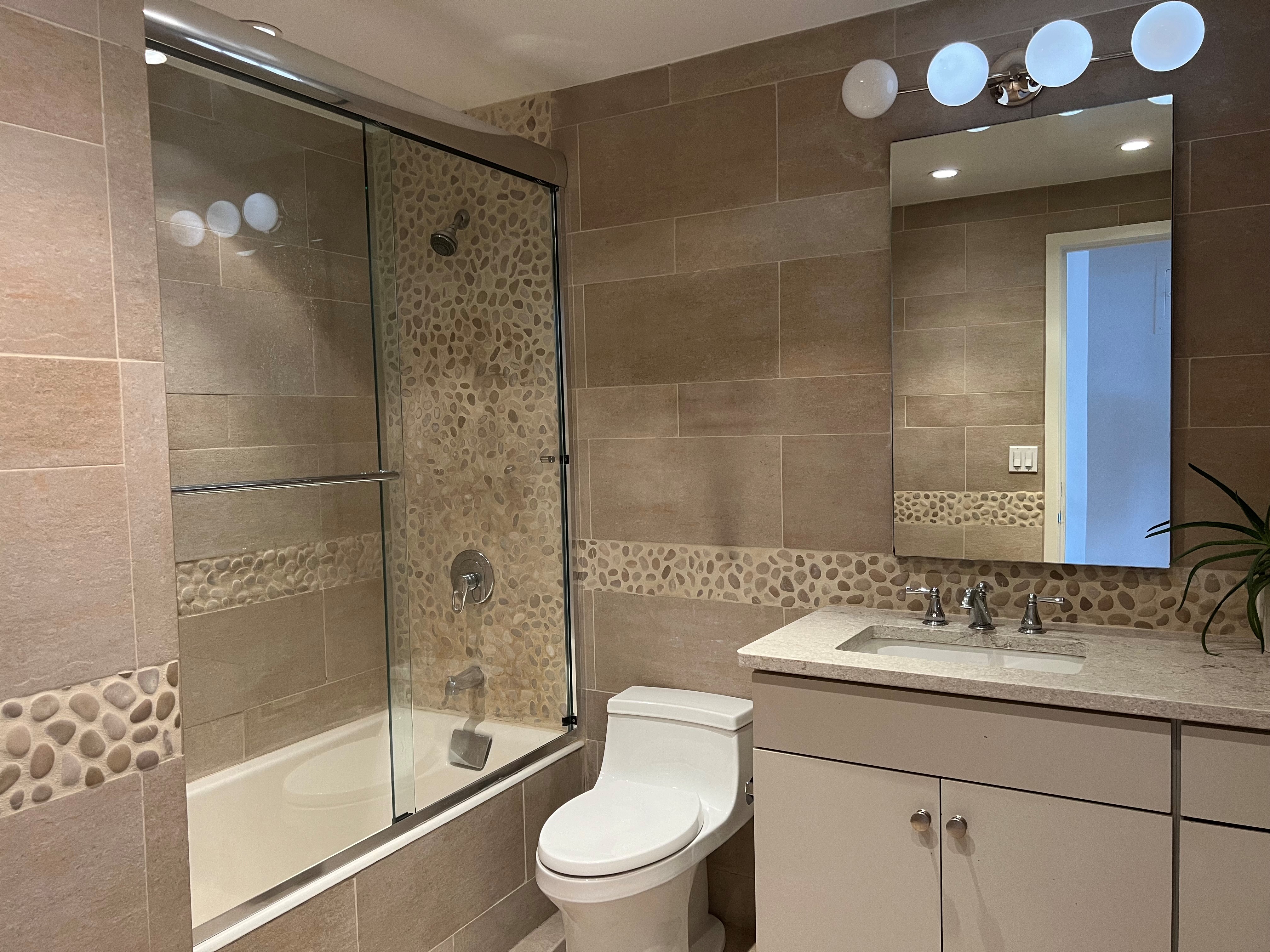 60 East 8th Street, Unit 23D Manhattan, NY 10003 - Photo 8 of 16 a bathroom with a shower sink vanity mirror and toilet