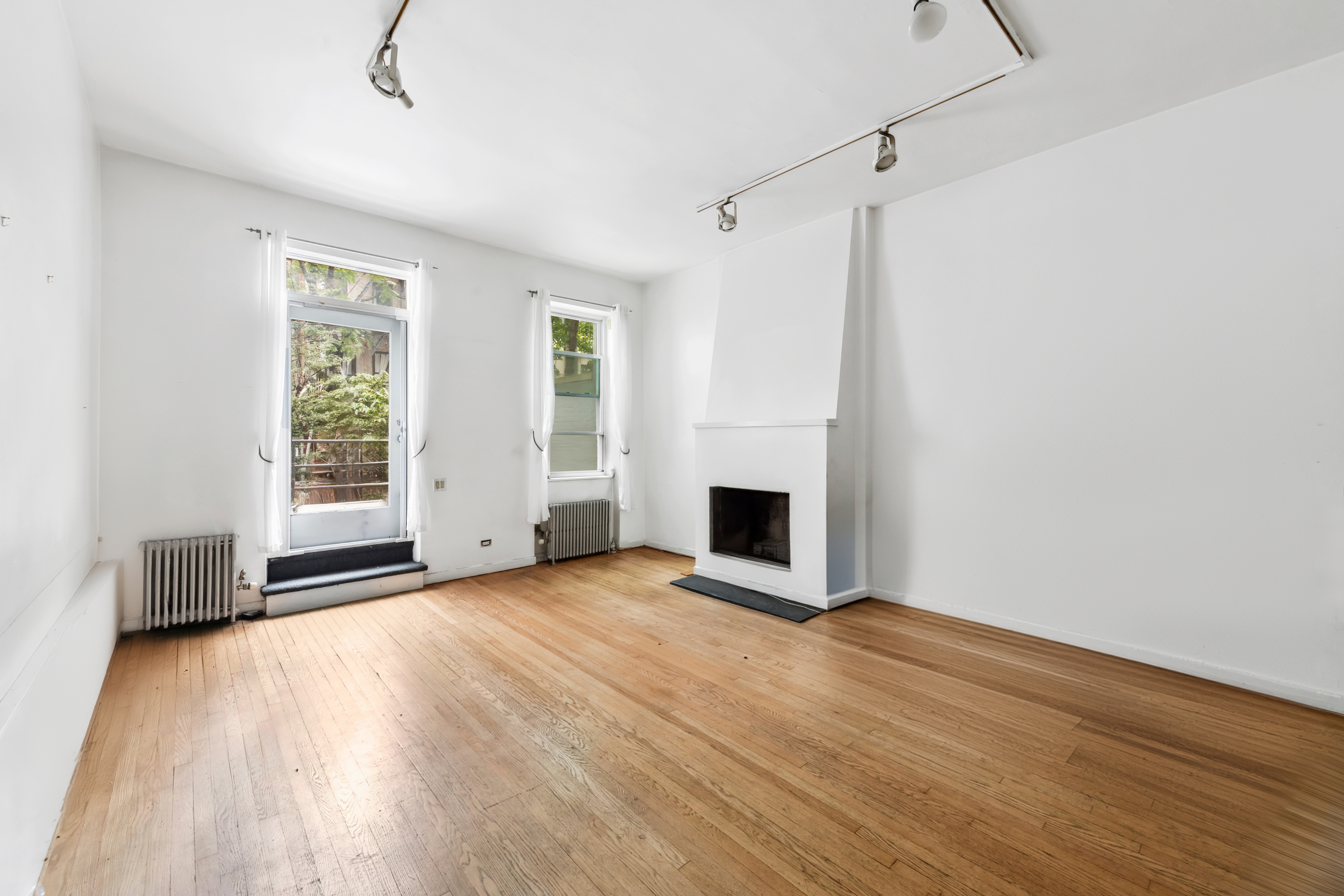 209 East 48th Street Manhattan, NY 10017 - Photo 4 of 13 a view of empty room with wooden floor and fireplace