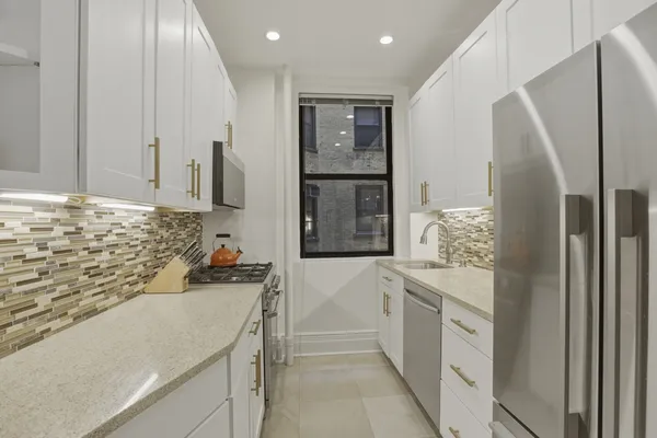 a kitchen with white cabinets and refrigerator