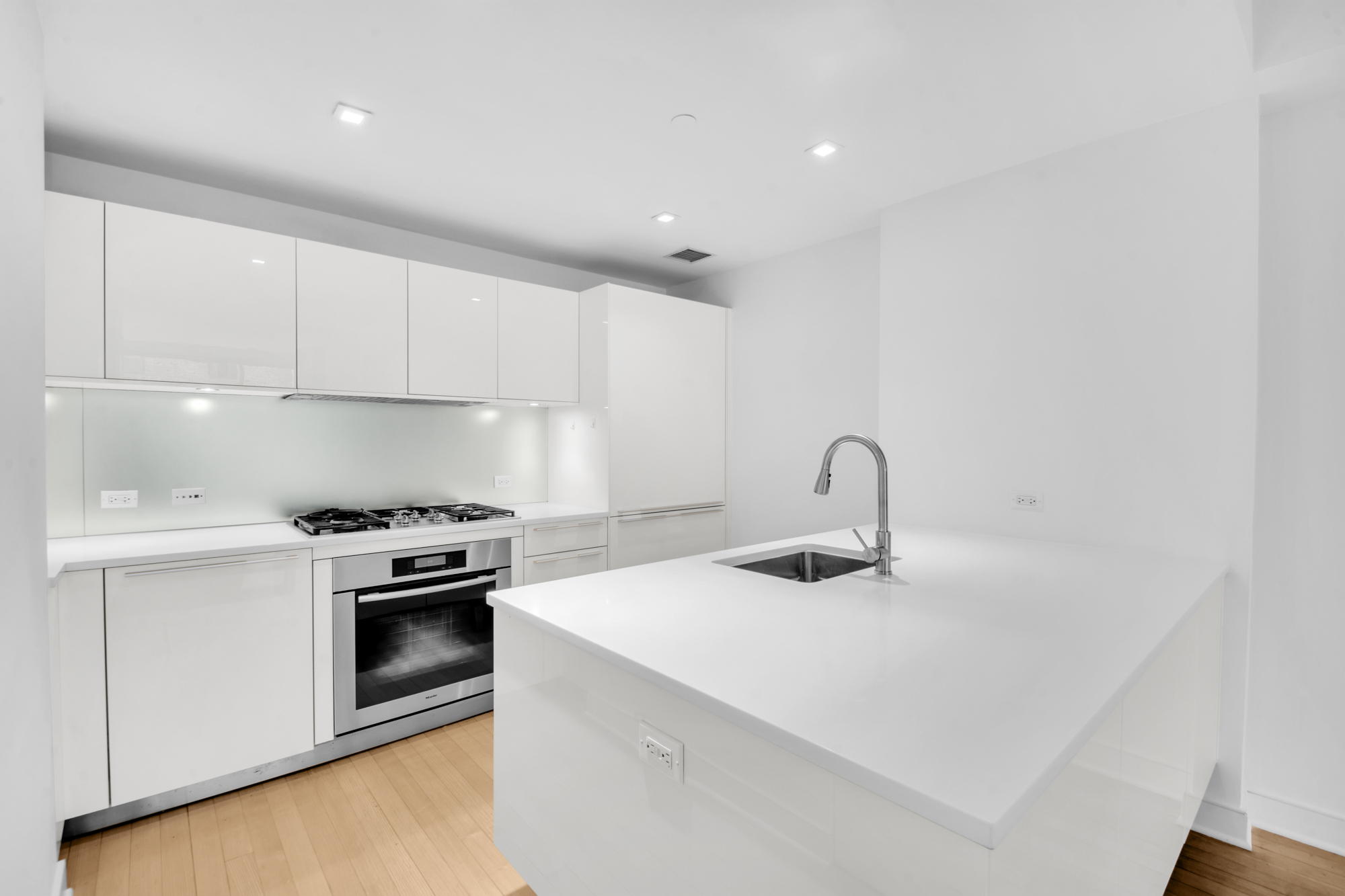 5 East 44th Street, Unit 5A Manhattan, NY 10017 - Photo 8 of 15 a kitchen with a sink a stove and white cabinets