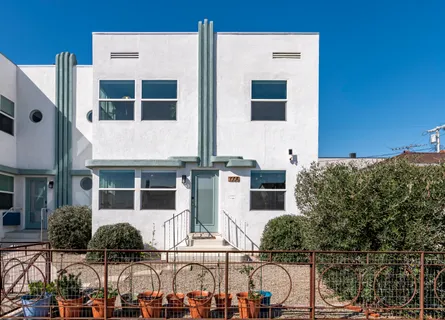 a front view of a building with glass windows and plants