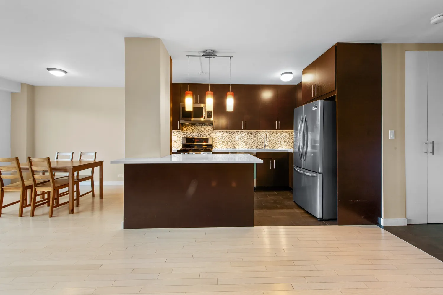 a kitchen with stainless steel appliances kitchen island granite countertop a refrigerator a stove a sink and a dining table with wooden floor